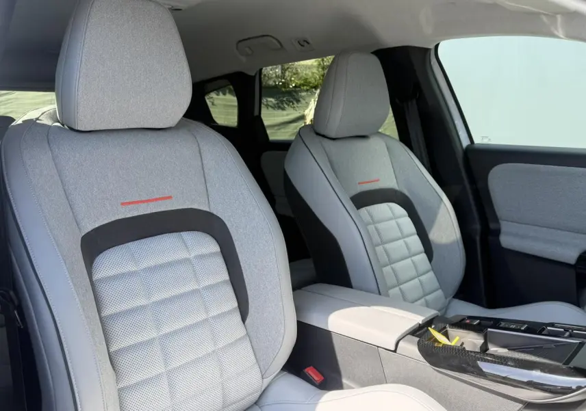 Vue intérieure des sièges avant gris clair avec inserts textiles et accoudoir central du Citroën C5 Aircross 2025.