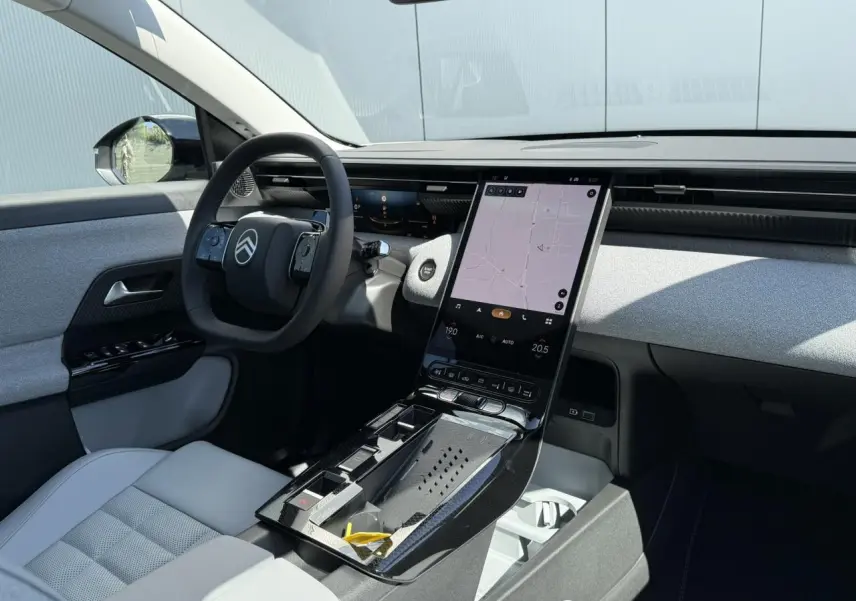 Vue intérieure côté conducteur du Citroën C5 Aircross 2025, tableau de bord clair avec écran tactile vertical et sellerie grise.