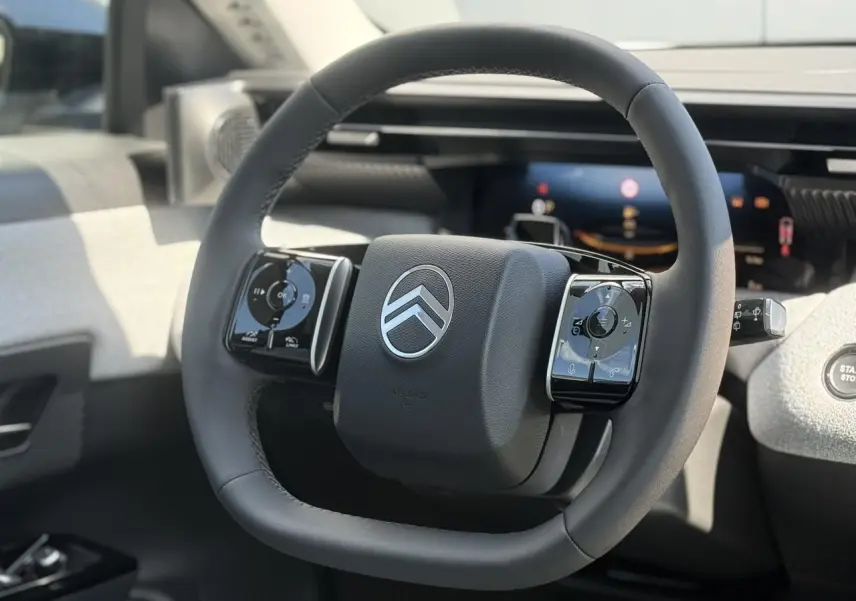 Vue rapprochée du volant noir multifonctions du Citroën C5 Aircross 2025 avec tableau de bord numérique en arrière-plan.