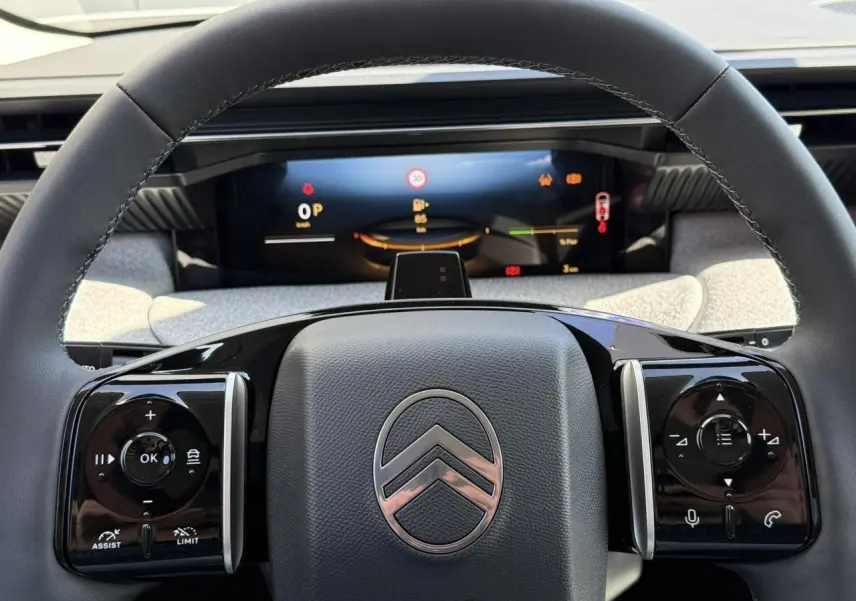 Vue rapprochée du volant noir brillant de la Citroën C5 Aircross 2025 avec commandes intégrées et tableau de bord numérique.