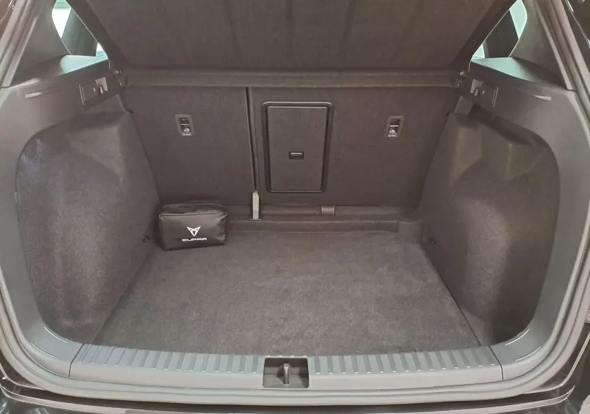 Coffre ouvert du CUPRA Ateca 2024 noir magique, vue arrière montrant un espace de rangement avec trousse de secours CUPRA.