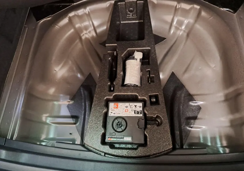 Vue intérieure du coffre du CUPRA Ateca 2024 noir magique, montrant le rangement pour kit de réparation pneus.