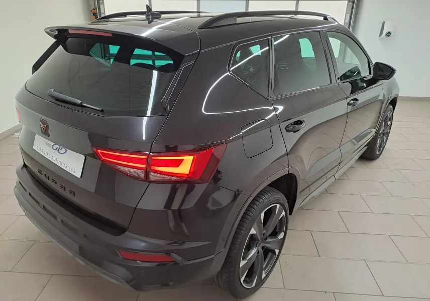 Vue 3/4 arrière droite du CUPRA Ateca 1.5 TSI 150 DSG7 2024 en noir magique avec feux arrière allumés et jantes sport.
