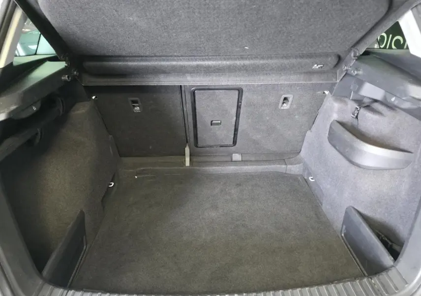 Coffre ouvert du Skoda Karoq blanc 2024, montrant un espace de rangement propre et bien agencé avec trappe centrale.