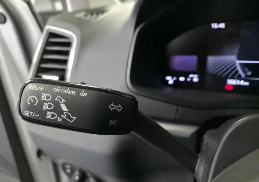 Gros plan sur la commande de régulateur de vitesse et clignotants côté gauche du tableau de bord noir du Skoda Karoq 2024.