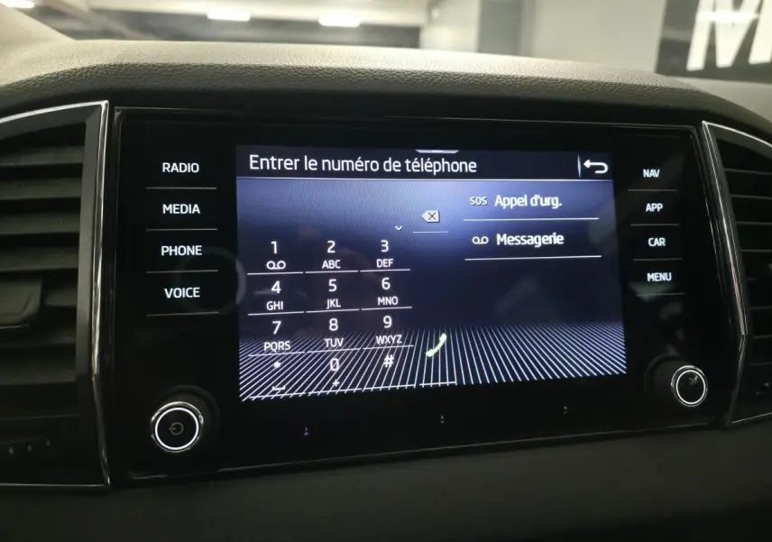 Écran tactile central du tableau de bord du Skoda Karoq 2024 affichant le clavier pour entrer un numéro de téléphone.
