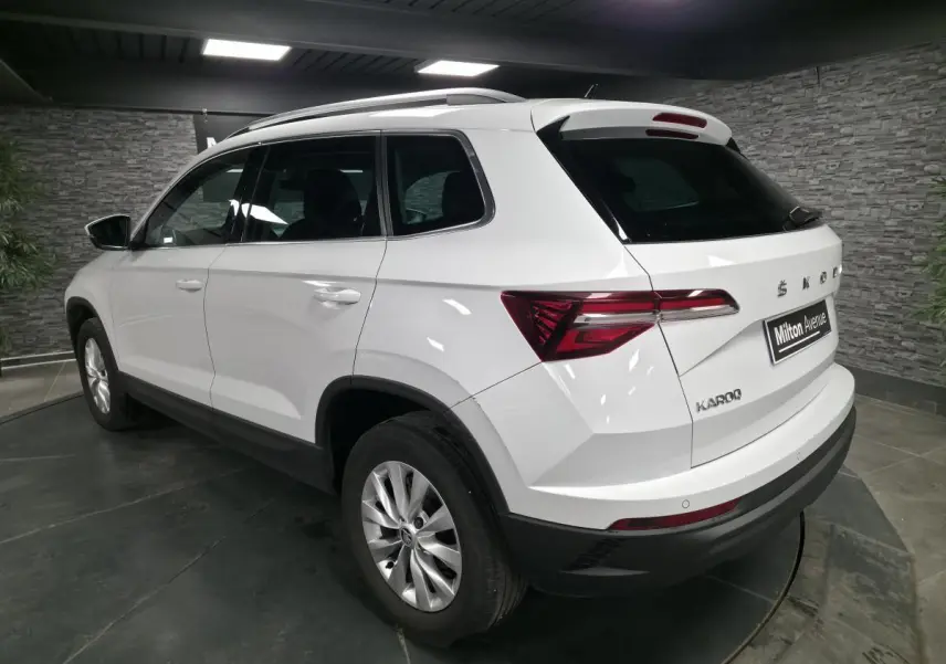 Vue 3/4 arrière droite d'un SUV SKODA KAROQ blanc avec feux arrière LED et jantes alliage 16 pouces.