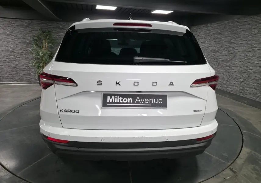 Vue arrière d'un SUV SKODA KAROQ blanc 2024 avec feux arrière LED et logo ŠKODA visible sur le hayon.