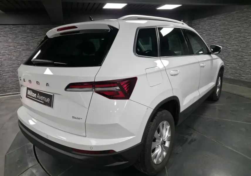 Vue 3/4 arrière droite d'un SUV Skoda Karoq blanc avec feux arrière LED et jantes alliage 16 pouces.
