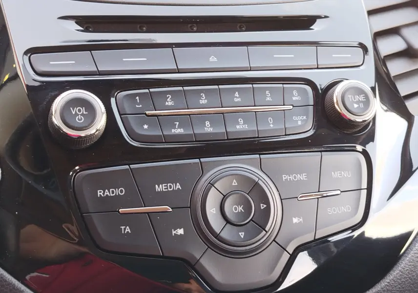 Gros plan sur la console centrale noire brillante de la Ford KA+ 2020, avec commandes radio et boutons multifonctions.