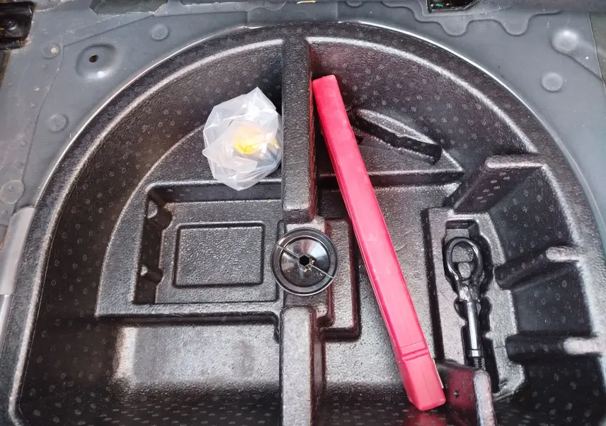 Vue plongeante sur le rangement sous le coffre d'une Ford KA+ 2020, avec un triangle de signalisation rouge et un crochet de remorquage.