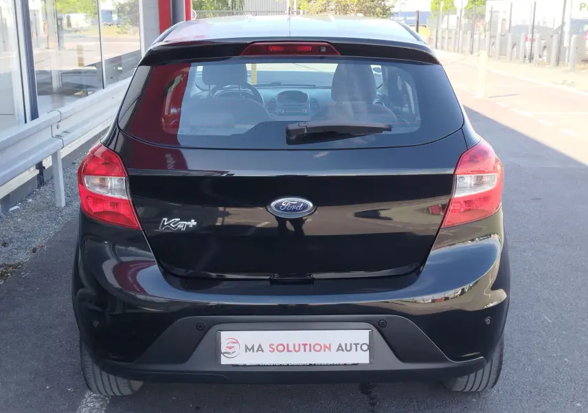 Vue arrière d'une Ford KA+ noire Shadow avec toit blanc, montrant les feux arrière et le logo Ford central.