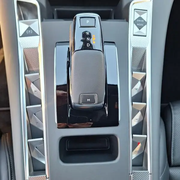 Vue plongeante sur la console centrale grise du DS7 BlueHDi 130 EAT8 2025, avec levier de vitesse automatique et boutons triangulaires.