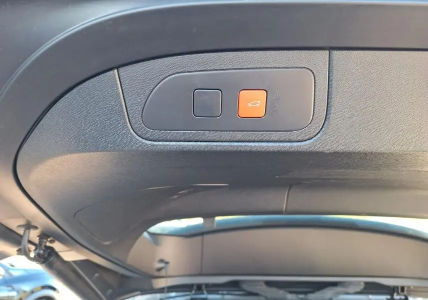 Boutons de commande de hayon électrique sur le panneau intérieur du coffre d’un DS7 gris 2025.