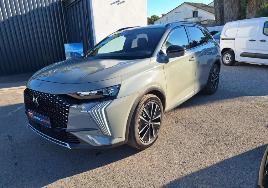 DS7 BlueHDi 130 EAT8 gris vu en 3/4 avant droit, avec calandre noire à motifs et feux LED distinctifs en forme de flèche.