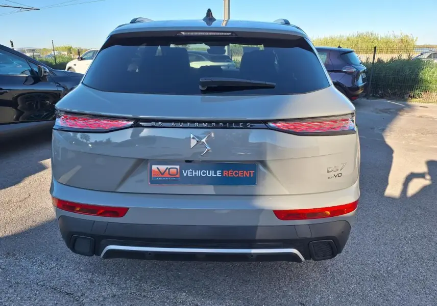 Vue arrière d'un DS7 gris 2025 avec feux arrière allongés et logo DS Automobiles au centre.