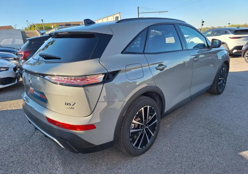 Vue 3/4 arrière droite du SUV DS7 gris 2025 avec feux arrière distinctifs et jantes noires bicolores.