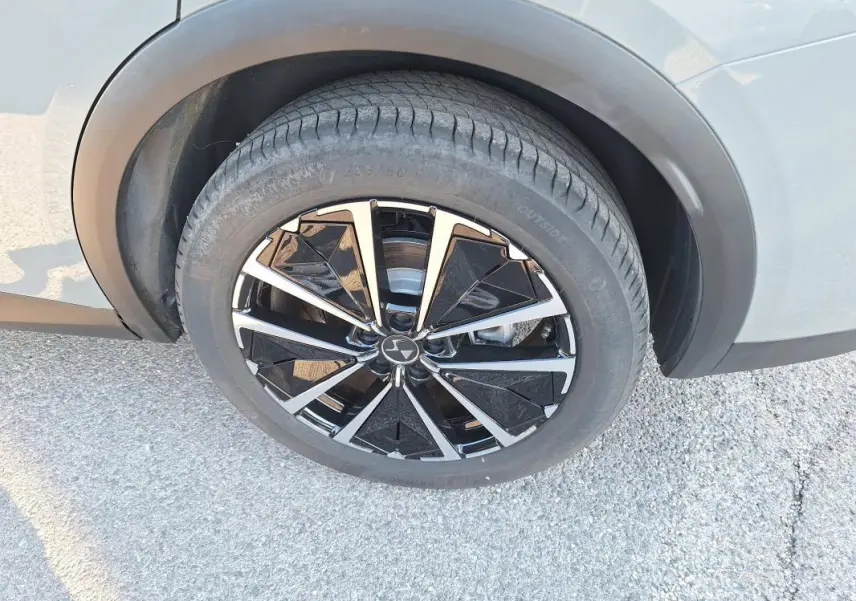 Gros plan sur la roue avant gauche du DS7 2025 gris, avec jante noire et argentée au design géométrique distinctif.