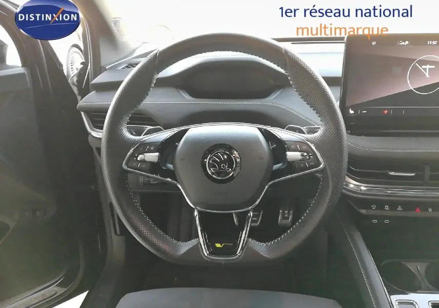 Vue intérieure centrée sur le volant perforé noir du Skoda Enyaq Coupe RS électrique avec tableau de bord moderne.