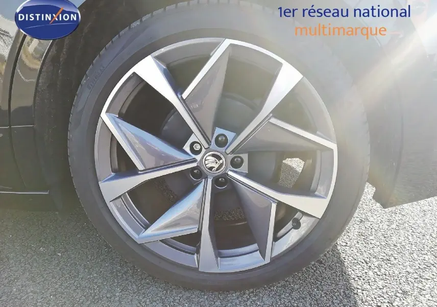 Gros plan sur la jante en alliage gris à cinq branches doubles du Skoda Enyaq noir métal, avec logo central visible.