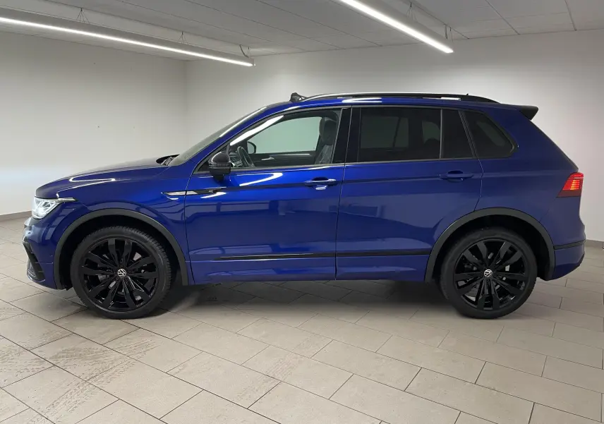 Vue de profil côté gauche d'un Volkswagen Tiguan Bleu Lapiz avec jantes noires et vitres arrière surteintées.