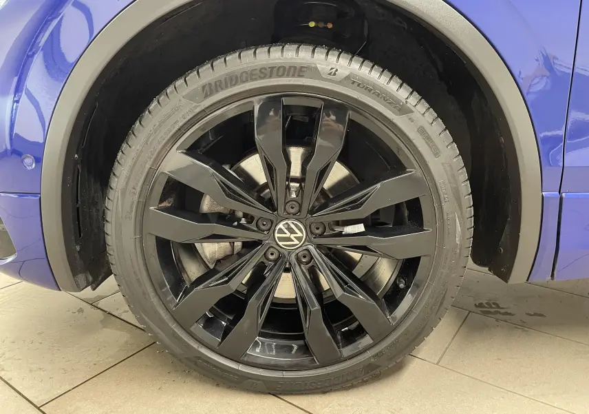 Gros plan sur la jante noire 20'' Suzuka du côté gauche d'un Volkswagen Tiguan Bleu Lapiz 2022.