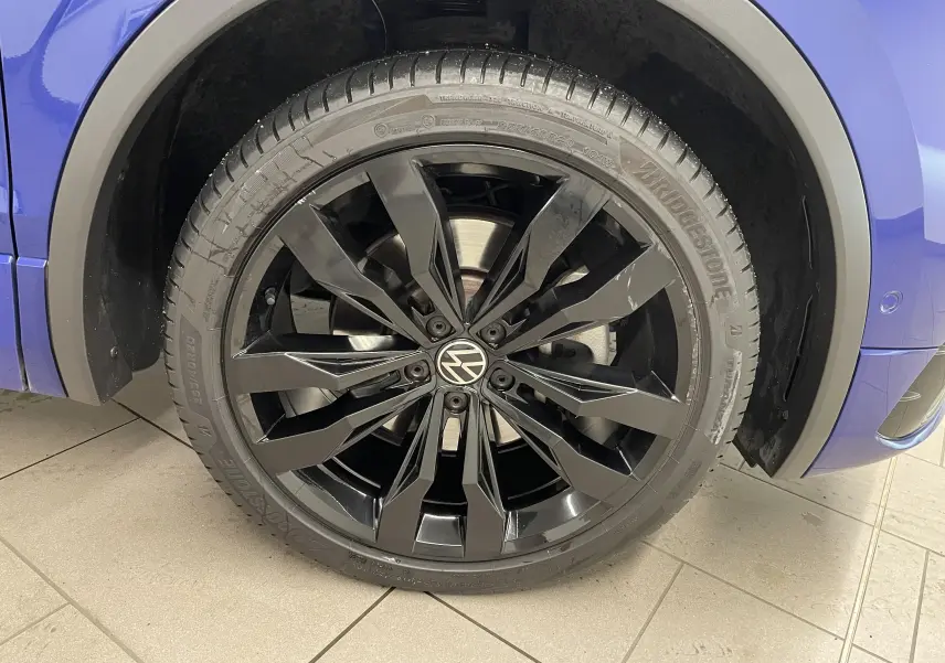 Gros plan sur la jante noire 20'' Suzuka du Volkswagen Tiguan Bleu Lapiz, avec pneu Bridgestone visible côté avant droit.