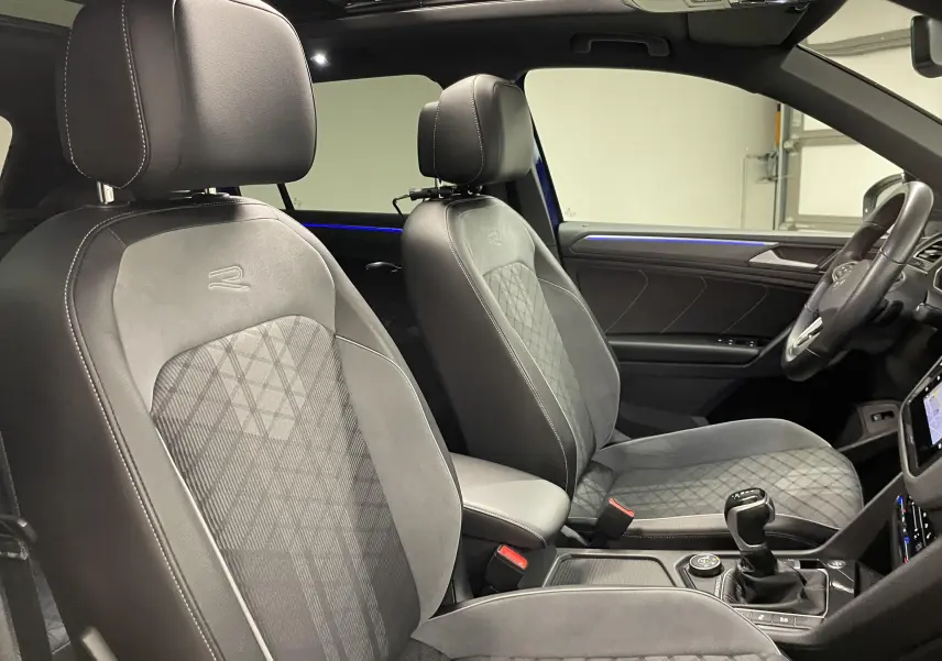 Vue intérieure côté droit du Volkswagen Tiguan 2.0 TDI 200ch R-Line 2022, sièges noirs avec surpiqûres et toit panoramique.