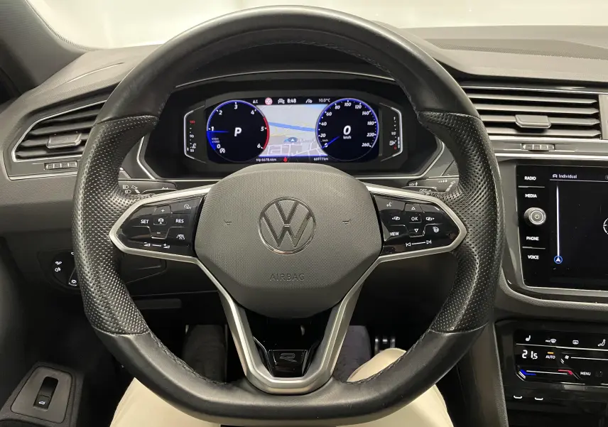 Vue intérieure centrée sur le volant cuir perforé noir et le tableau de bord numérique du Volkswagen Tiguan 2022.