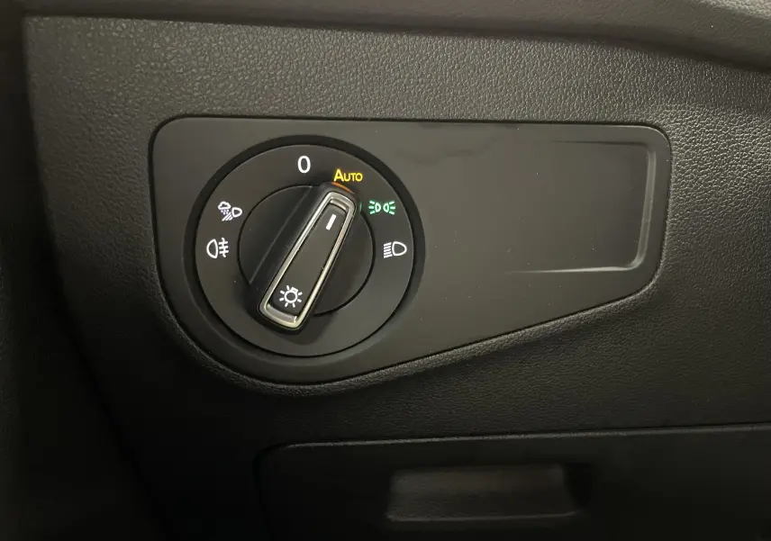 Commande des phares en gros plan sur tableau de bord noir du Volkswagen Tiguan Bleu Lapiz, version Black R-Line.