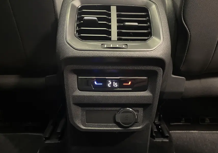 Détail de la console arrière noire du Volkswagen Tiguan 2022 avec réglage climatisation à 21,5°C et prise 12V.