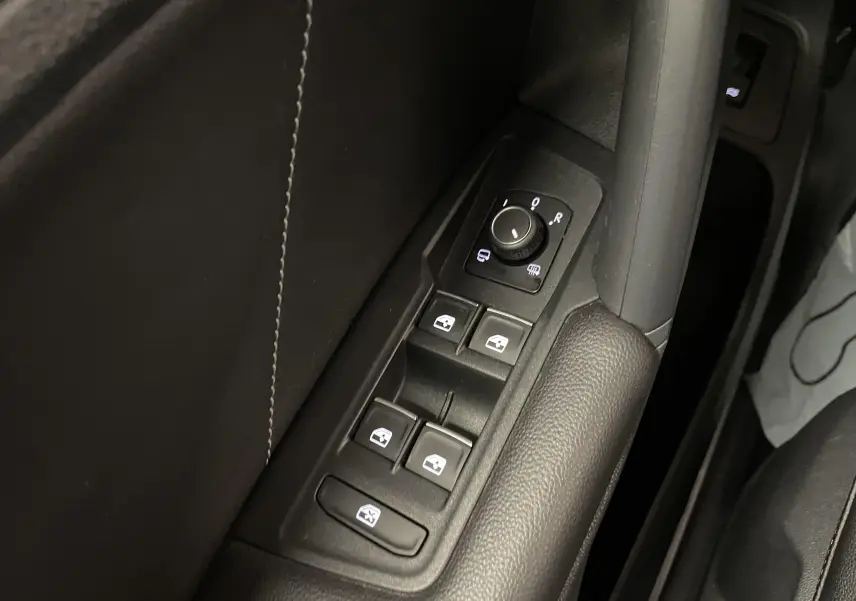 Gros plan sur les commandes de lève-vitres et réglage des rétroviseurs côté conducteur du Volkswagen Tiguan 2022 noir.