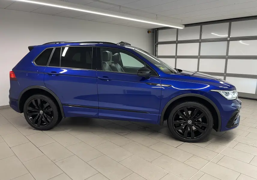 Vue de profil côté gauche d'un Volkswagen Tiguan Bleu Lapiz avec jantes noires et vitres arrière surteintées.