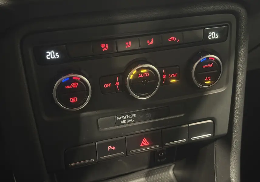 Détail du tableau de bord noir de la Volkswagen Coccinelle 2013, montrant les commandes de climatisation automatique.