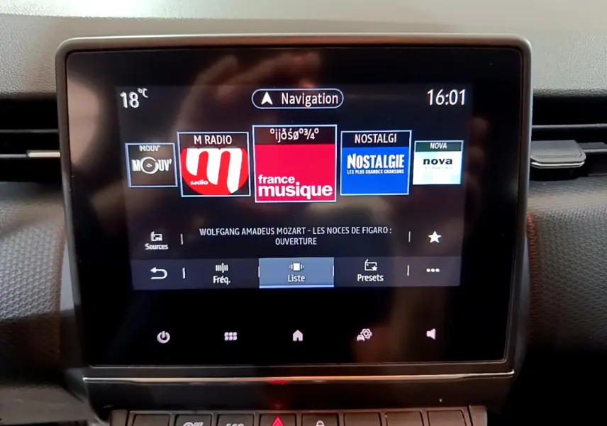 Écran tactile central de la Renault Clio Business blanc, affichant les stations radio et la navigation, vue de face.