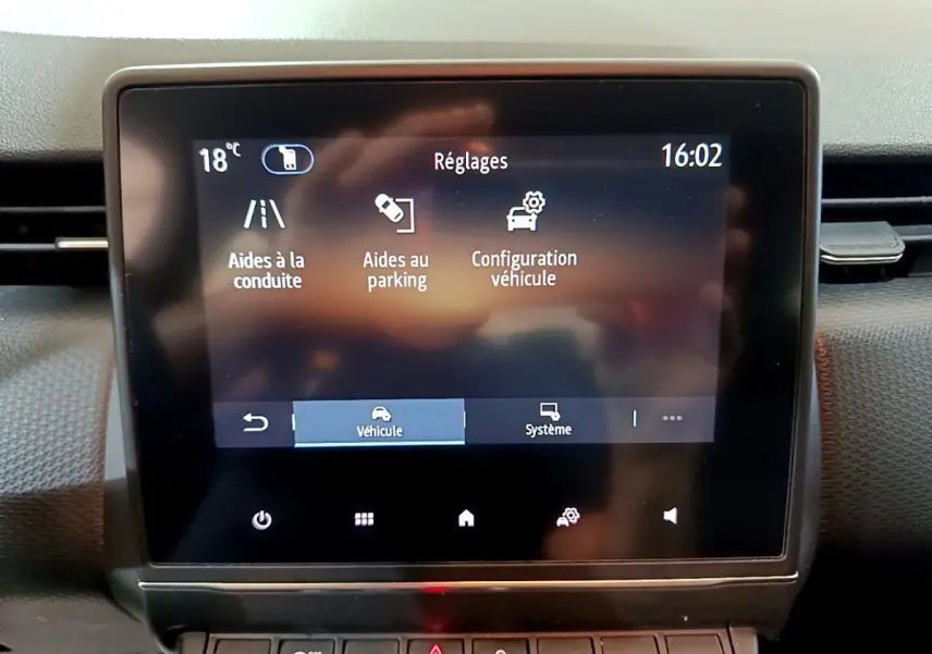 Écran tactile central de la Renault Clio Business blanc, affichant les réglages d’aides à la conduite et parking.