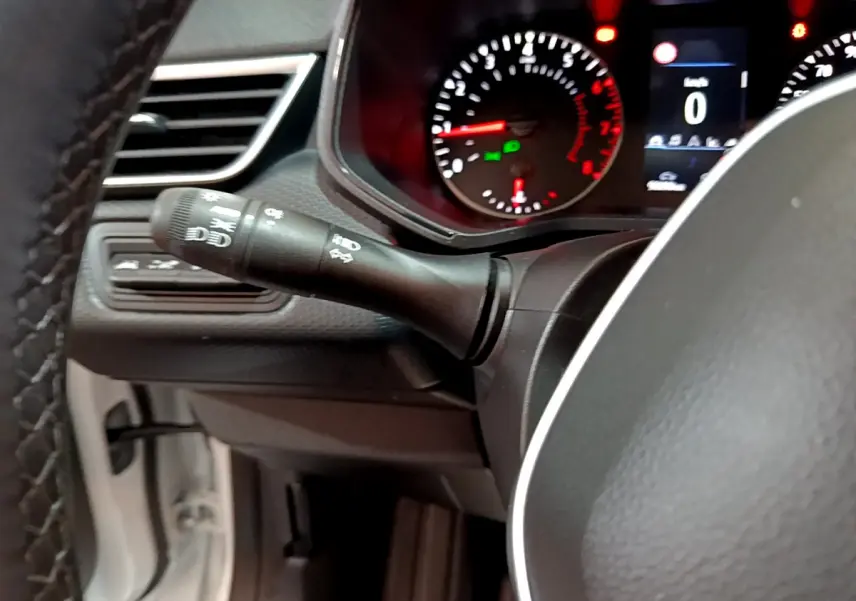 Gros plan sur le commodo gauche et le tableau de bord numérique de la Renault Clio Business TCe 90 blanche de 2021.