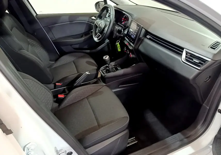 Vue intérieure côté conducteur d'une Renault Clio Business TCe 90 blanche, avec tableau de bord tactile et sièges tissu noirs.