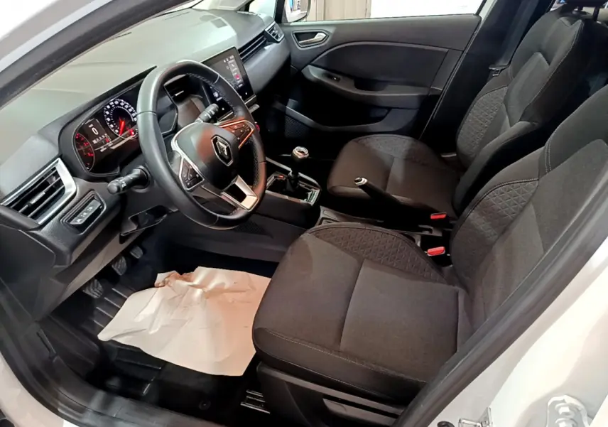 Vue intérieure côté conducteur de la Renault Clio Business TCe 90 2021 blanche, avec tableau de bord et sièges noirs.