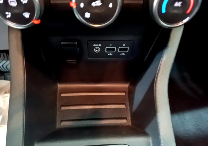 Vue rapprochée de la console centrale noire de la Renault Clio Business TCe 90, avec prises USB et commandes de climatisation.