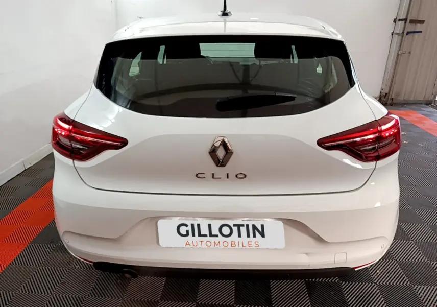 Vue arrière d'une Renault Clio blanche 2021 avec feux LED et logo centré dans un garage.