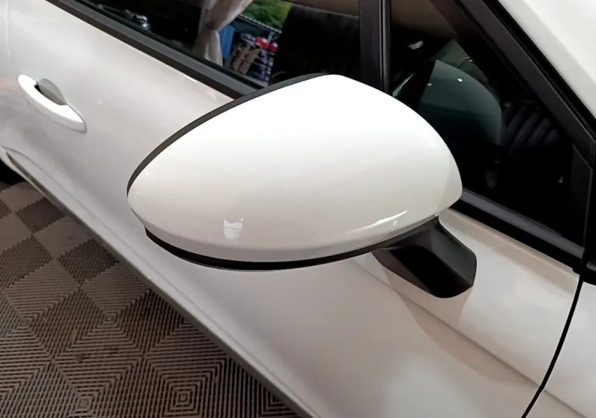 Gros plan sur le rétroviseur côté gauche blanc d'une Renault Clio Business TCe 90, avec portière et poignée visibles.