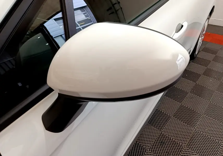 Gros plan sur le rétroviseur côté gauche blanc d'une Renault Clio Business TCe 90 2021, avec porte et partie latérale visibles.