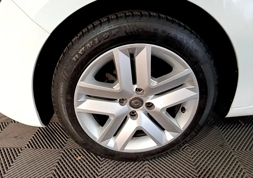 Vue rapprochée de la roue arrière droite d'une Renault Clio Business TCe 90 blanche, sur sol texturé.