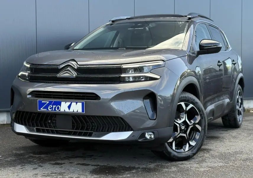 Citroën C5 Aircross gris Platinium en 3/4 avant droit avec jantes diamantées et toit ouvrant panoramique visible.