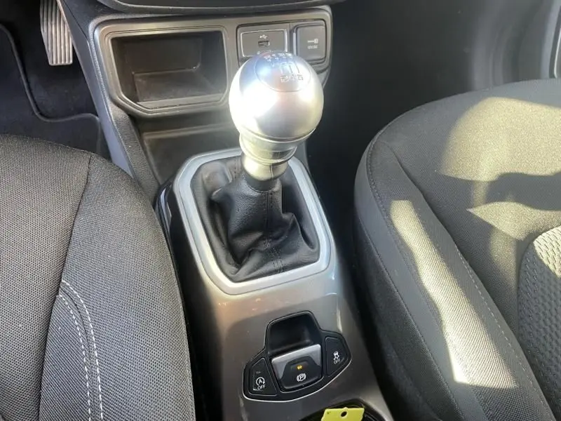Gros plan sur le levier de vitesse manuel argenté et la console centrale du Jeep Renegade blanc, sièges noirs visibles.