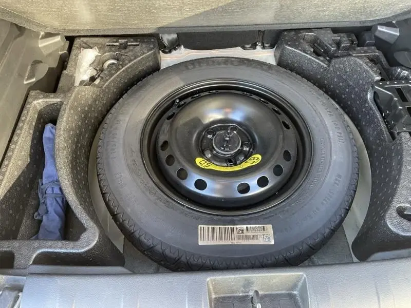 Vue en plongée sur la roue de secours noire dans le coffre du Jeep Renegade blanc 2019, version Limited essence.