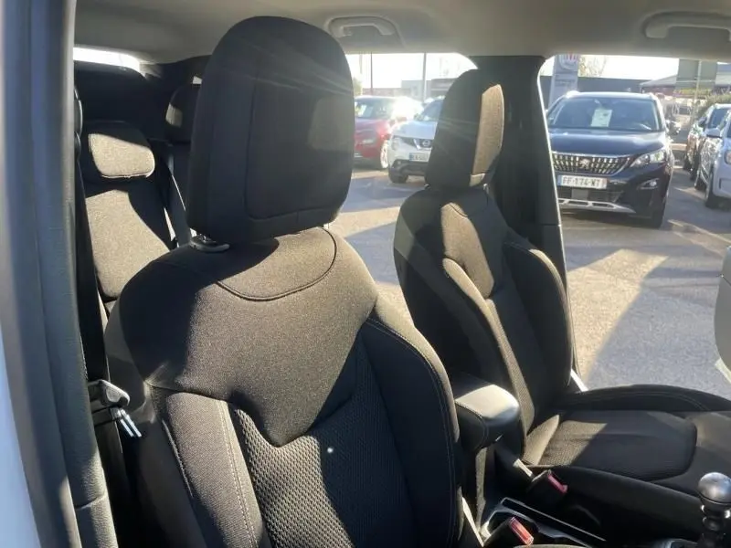 Vue intérieure côté conducteur du Jeep Renegade blanc 2019, mettant en valeur les sièges avant en tissu noir.