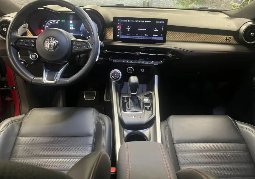 Vue intérieure avant de l'Alfa Romeo Tonale 2024, volant cuir noir, tableau de bord digital et console centrale moderne.