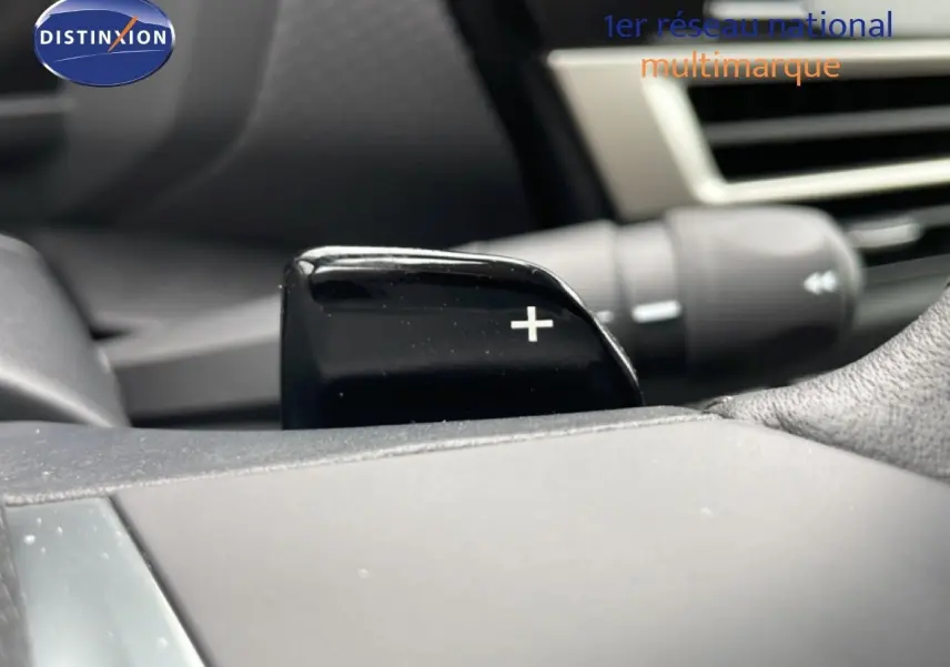 Gros plan sur la palette de changement de vitesse "+" côté droit du volant dans l'habitacle d'une Citroën C4 blanche.